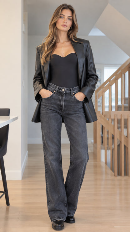 Front full-length view of woman wearing Black tailored faux leather blazer with sweetheart top and grey wide-leg jeans