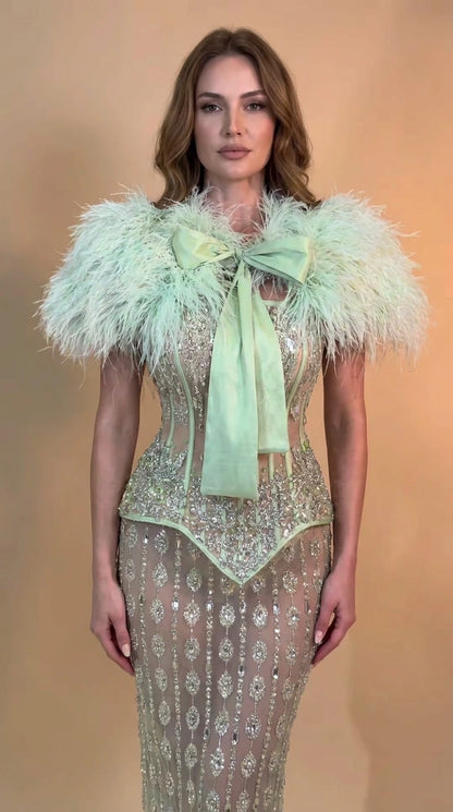 Front view of model wearing Mint Green feather trim sequin corset evening gown with front bow