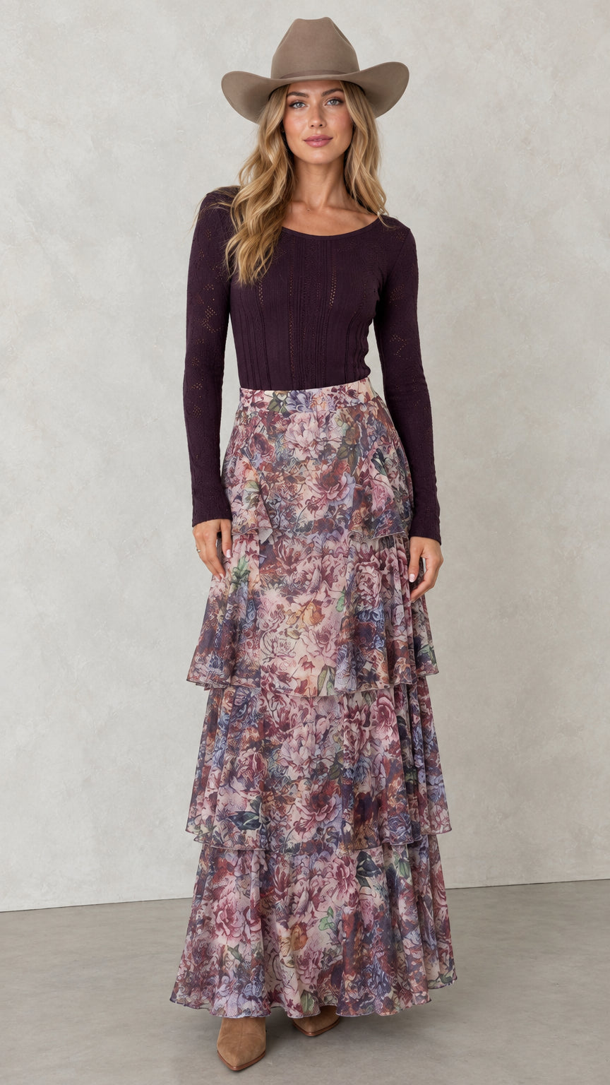 Front view of woman wearing Mauve Plum tiered floral maxi skirt with plum long sleeve top and hat