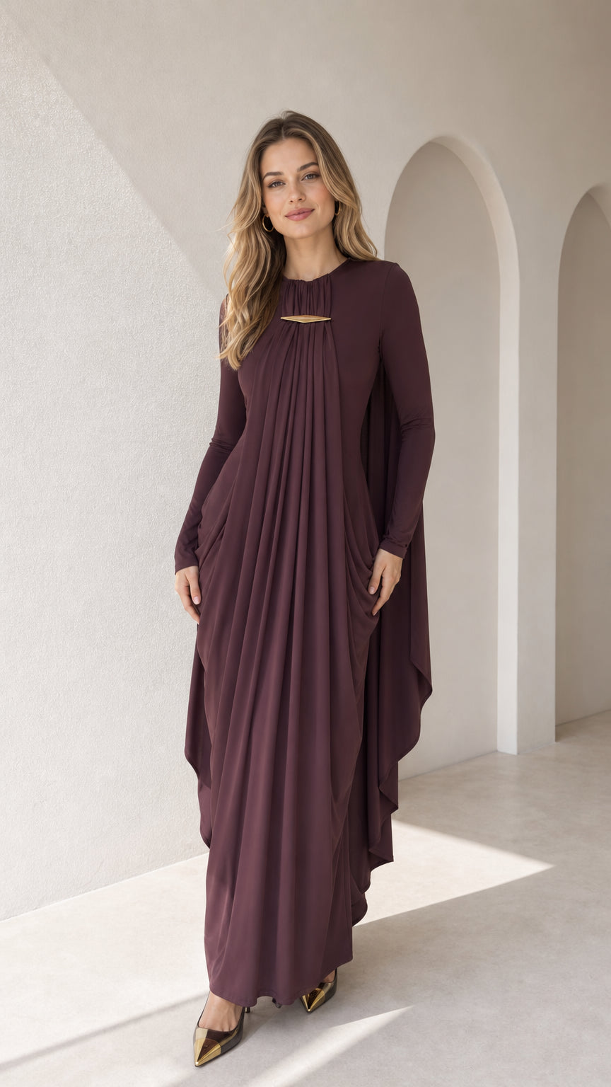 Front full view of woman wearing plum pleated cape maxi dress with gold hardware accent