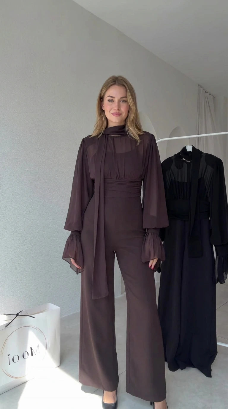 Full front view of model wearing Chocolate Brown tie-neck wide-leg jumpsuit with sheer lantern sleeves