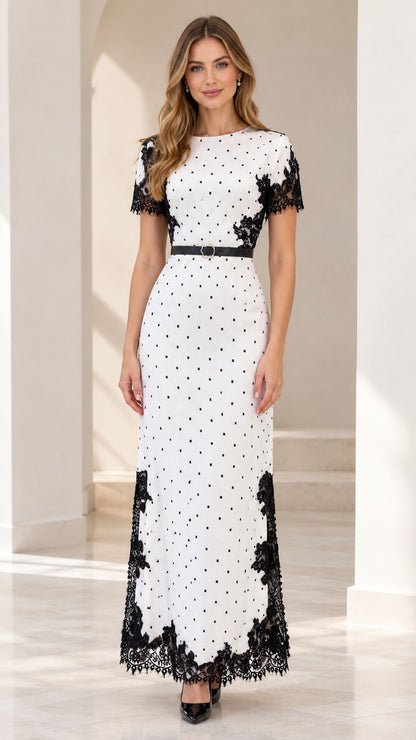Model wearing white polka dot maxi dress with black lace trim and belt - front view