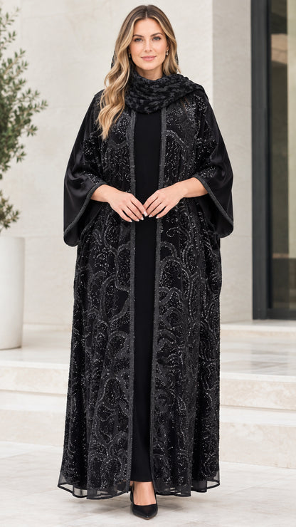Front full-length view of model wearing black sequin embroidered open front abaya set with matching scarf