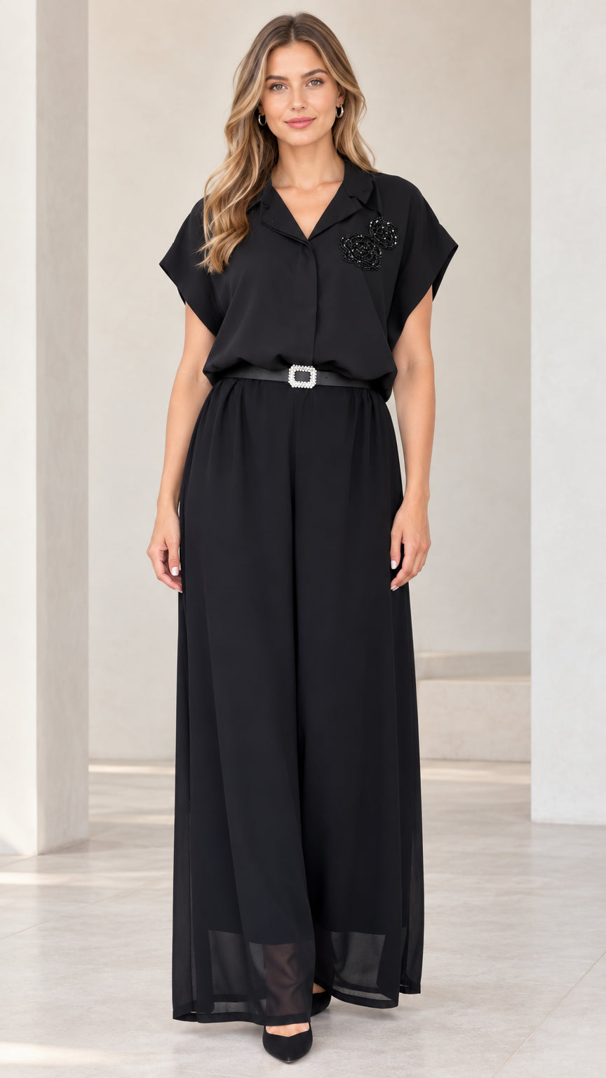 Front view of woman wearing black notch lapel wide-leg jumpsuit with crystal belt