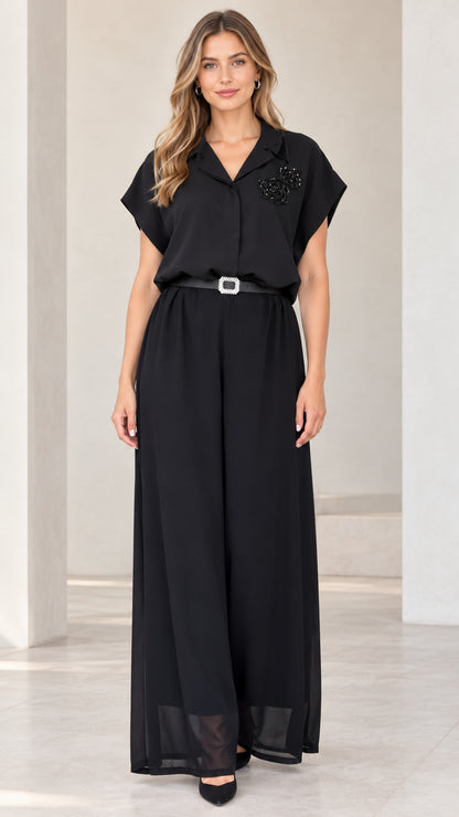 Front view of woman wearing black notch lapel wide-leg jumpsuit with crystal belt