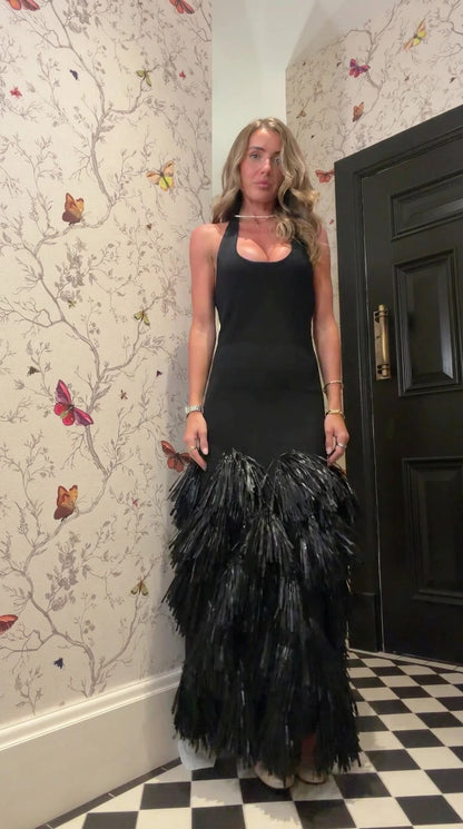 Front view of woman wearing black halter neck maxi dress with tiered fringe skirt