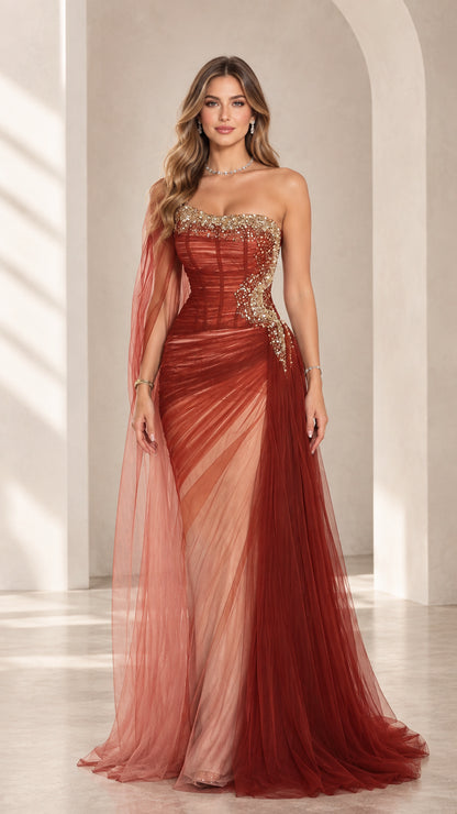 Front view of model wearing rust red strapless embellished corset tulle evening gown with cape drape