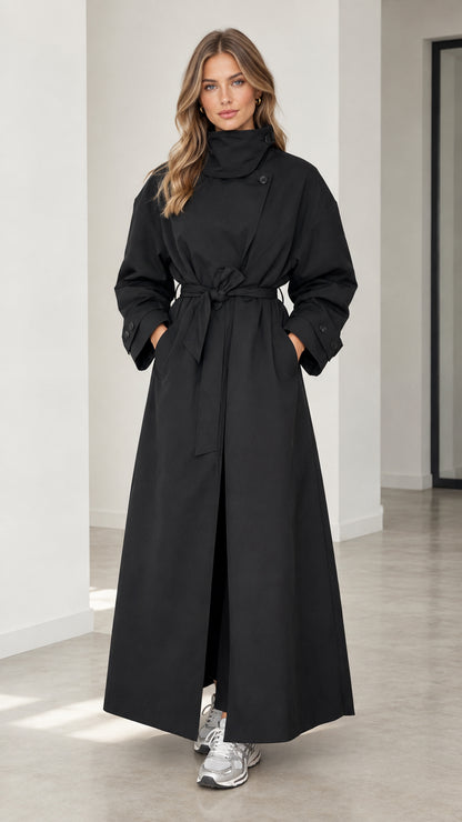 Front full view of woman wearing full-length black high neck belted maxi trench coat