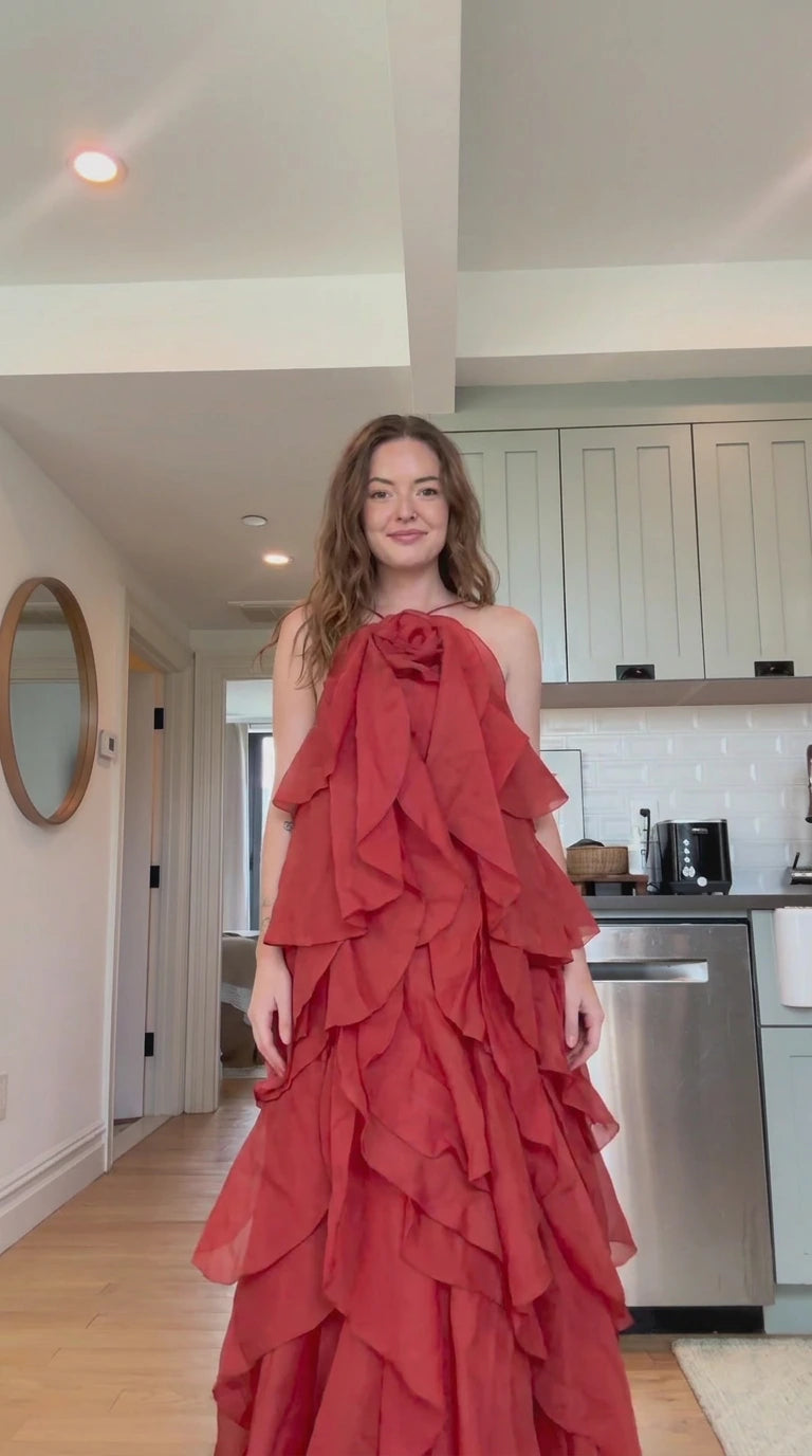 Front view of model wearing rust red tiered ruffle halter maxi dress with rosette detail