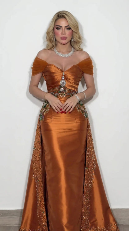 Front view of model wearing rust orange off-the-shoulder satin evening gown with beaded waist