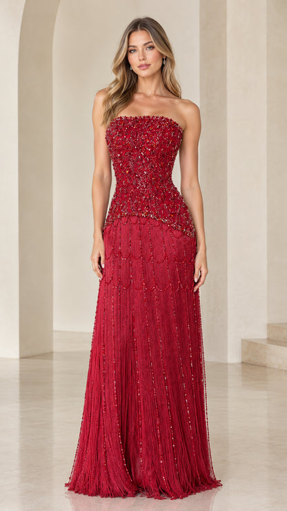 Front view of woman wearing strapless ruby red beaded evening gown with fringe skirt