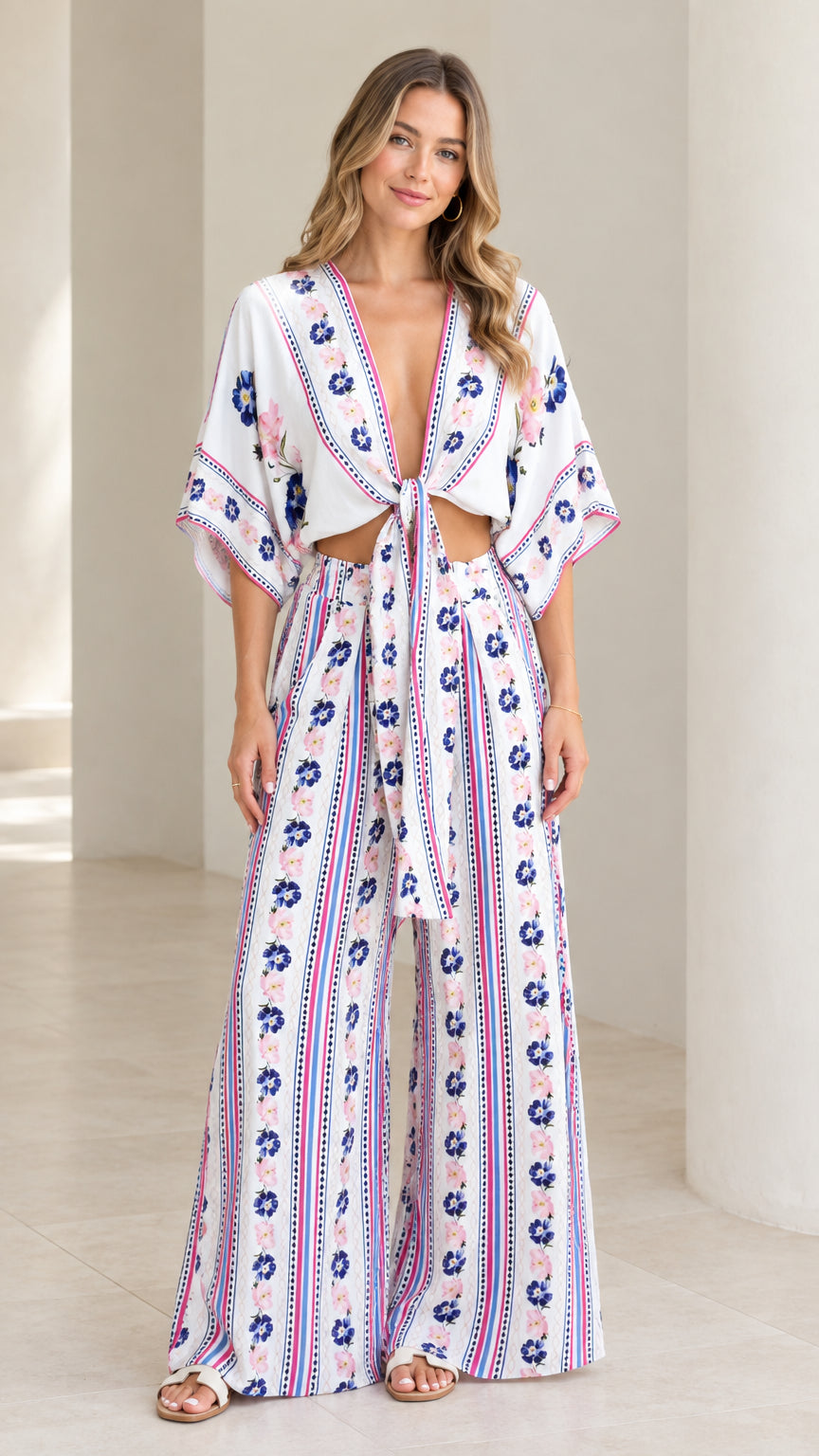 Full front view of model wearing white floral print tie-front crop top and wide-leg pants two-piece set