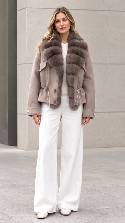 Front view of woman wearing taupe faux fur trim drawstring waist short coat with white trousers