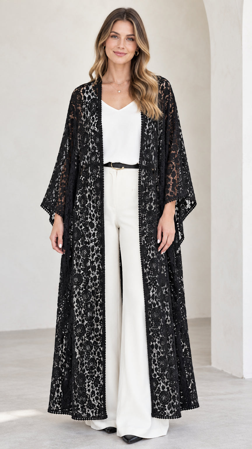 Front view of model wearing black floral lace maxi kimono duster with white trousers