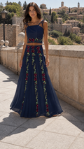 Model wearing a navy floral embroidered tie-strap crop top and flowing maxi skirt set