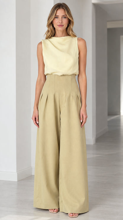 Front view of model wearing sleeveless draped top and wide-leg pleated jumpsuit in butter yellow and khaki