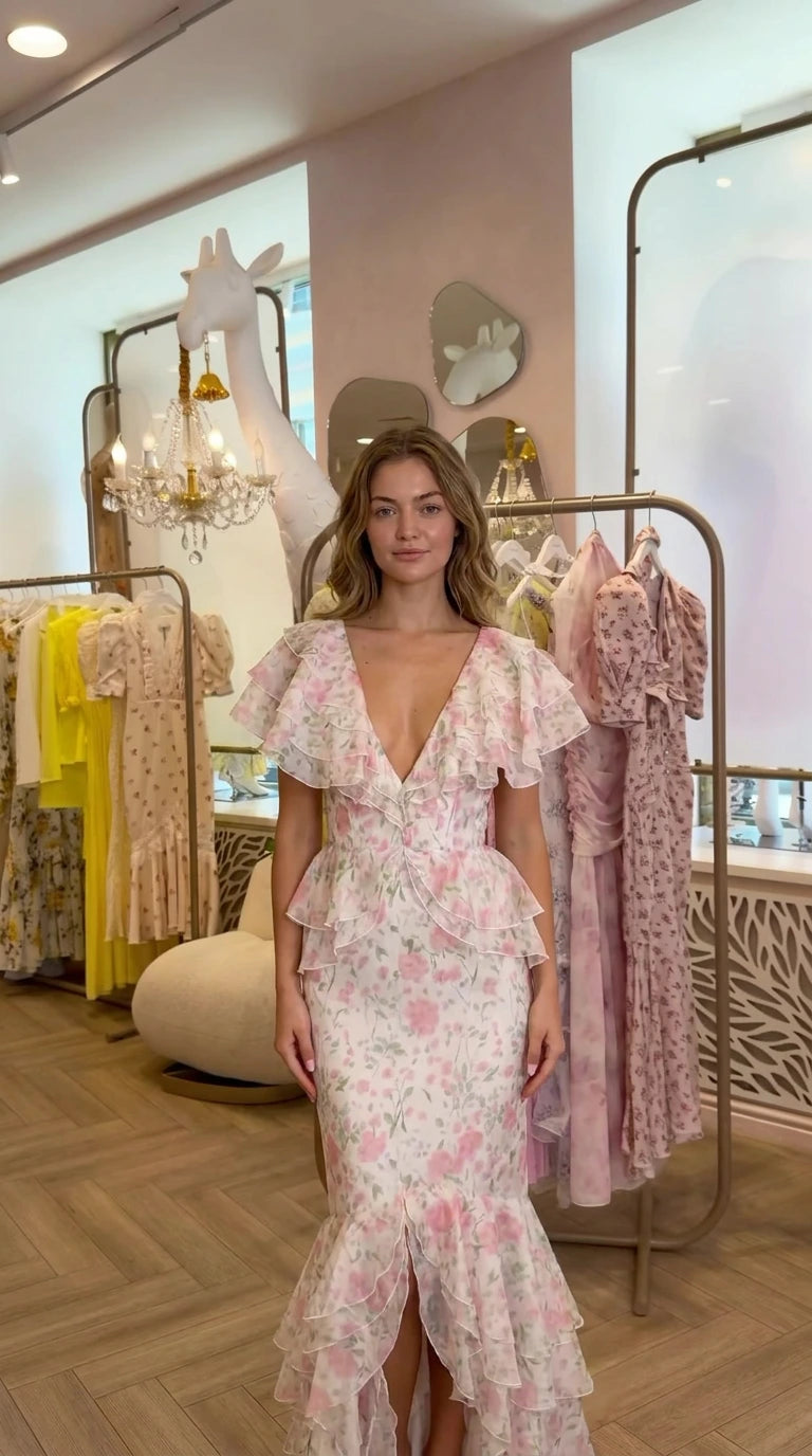 Front view of model wearing pink floral ruffle tiered mermaid maxi dress with deep V-neckline