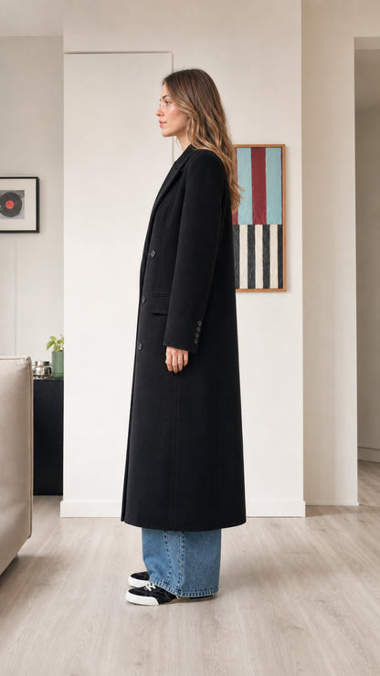 Side profile view of woman wearing black longline overcoat with wide-leg jeans