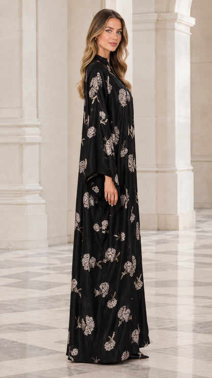 Side angle of woman wearing full length black floral embroidered abaya dress