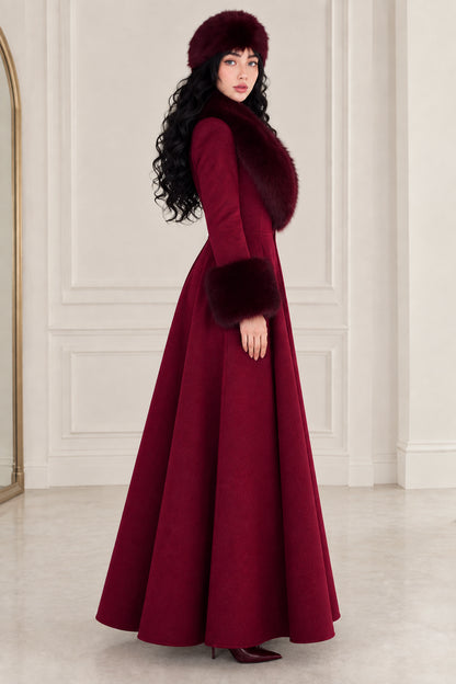 Side-angle view of woman in burgundy vintage-style full-length A-line coat