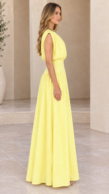 Side profile of model in yellow pleated asymmetrical waist maxi dress