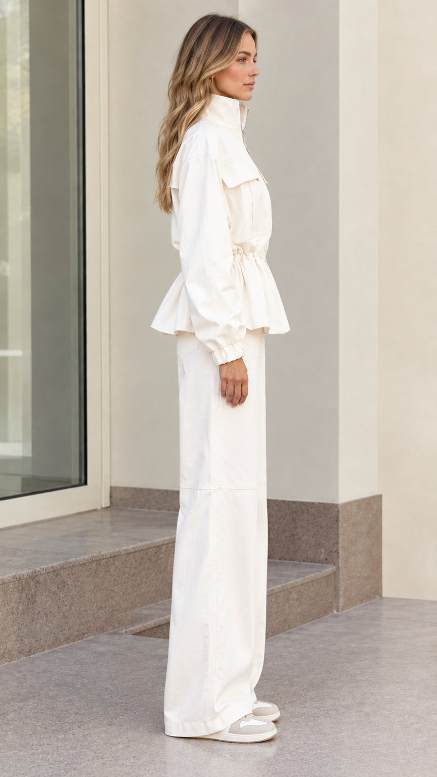 Side profile of women's off white cinched jacket and matching pants
