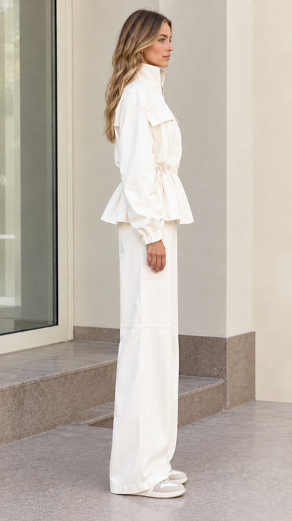 Side profile of women's off white cinched jacket and matching pants