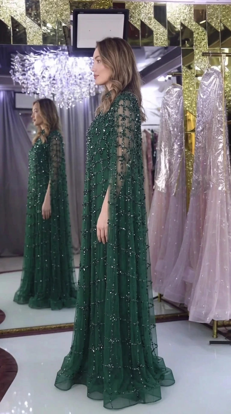 Side view of emerald green crystal embellished cape sleeve gown