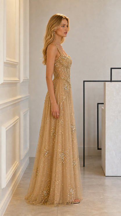 Side profile view of model posing in gold embellished formal gown