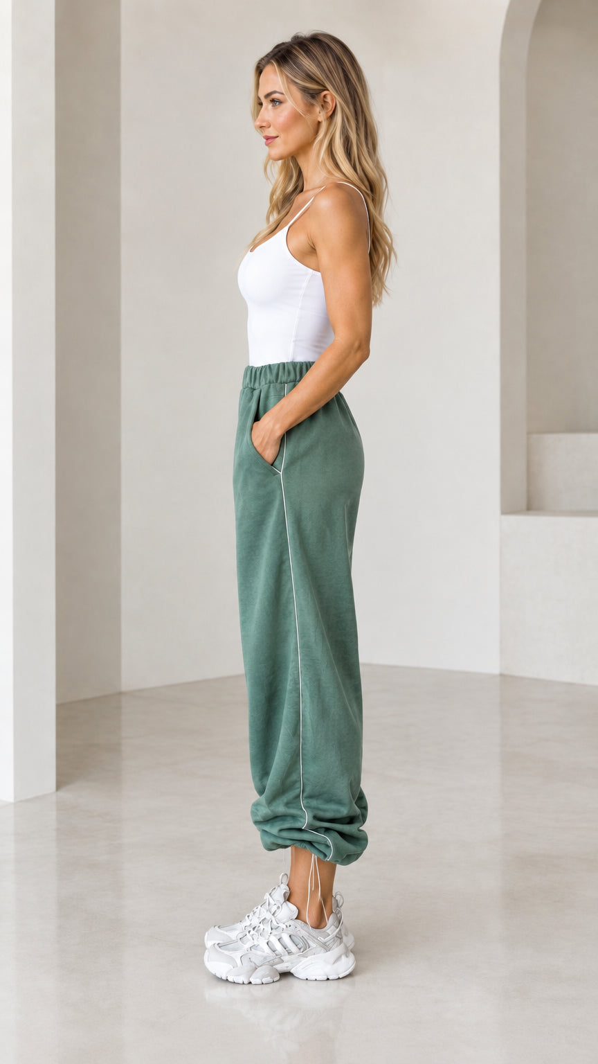 Side view of sage green joggers showing contrast white vertical piping
