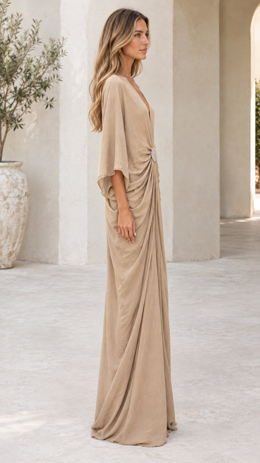Side profile view of woman wearing beige draped kaftan maxi dress