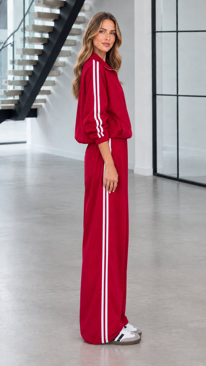 Side profile view of red zip-up jacket and wide-leg striped track pants