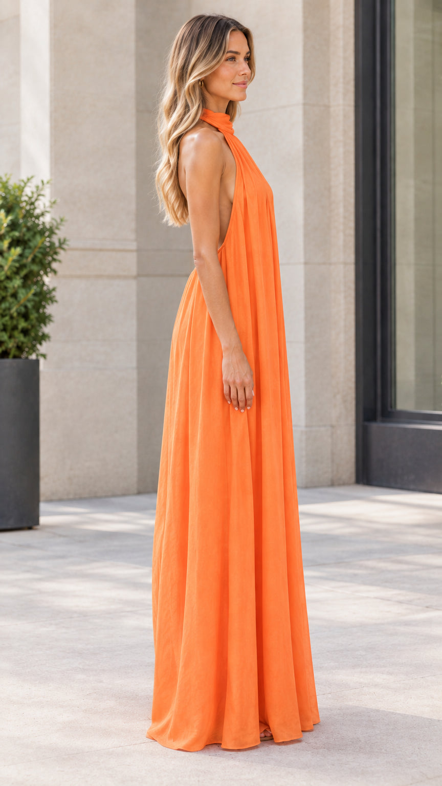 Side profile view of model wearing orange flowy wide-leg halter jumpsuit