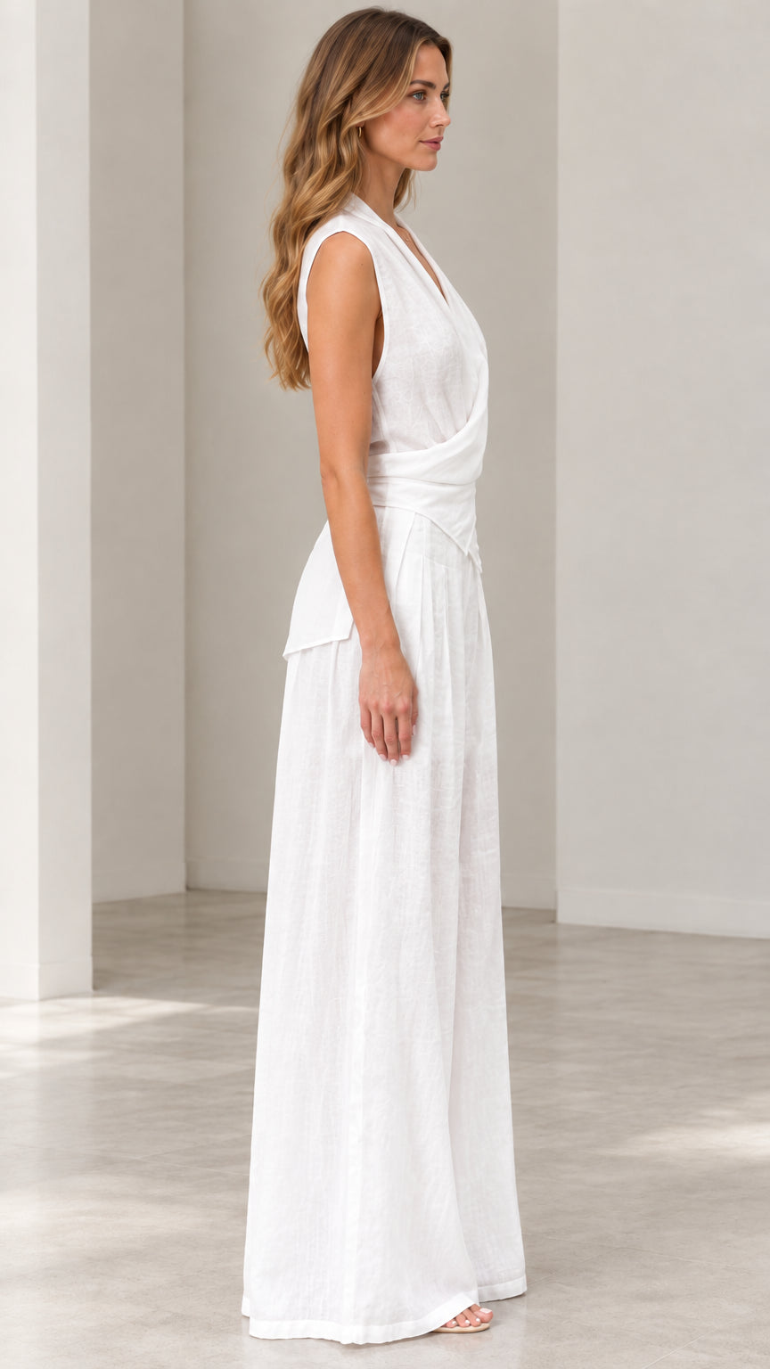 Side profile view of woman wearing white sleeveless wide-leg jumpsuit