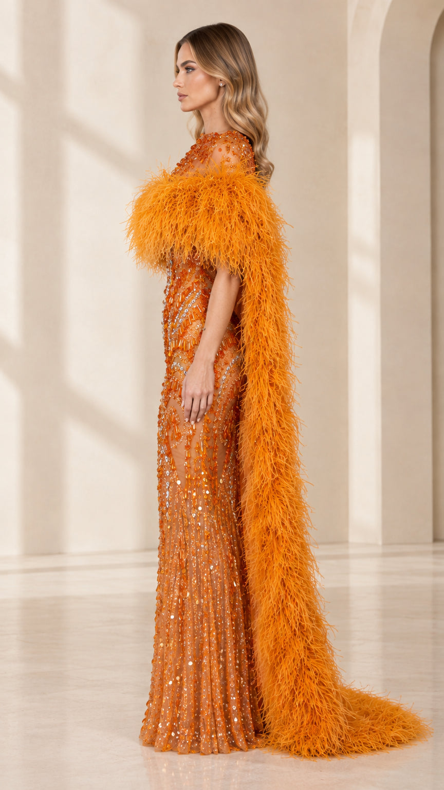 Side profile of model wearing orange embellished evening gown with long feather cape