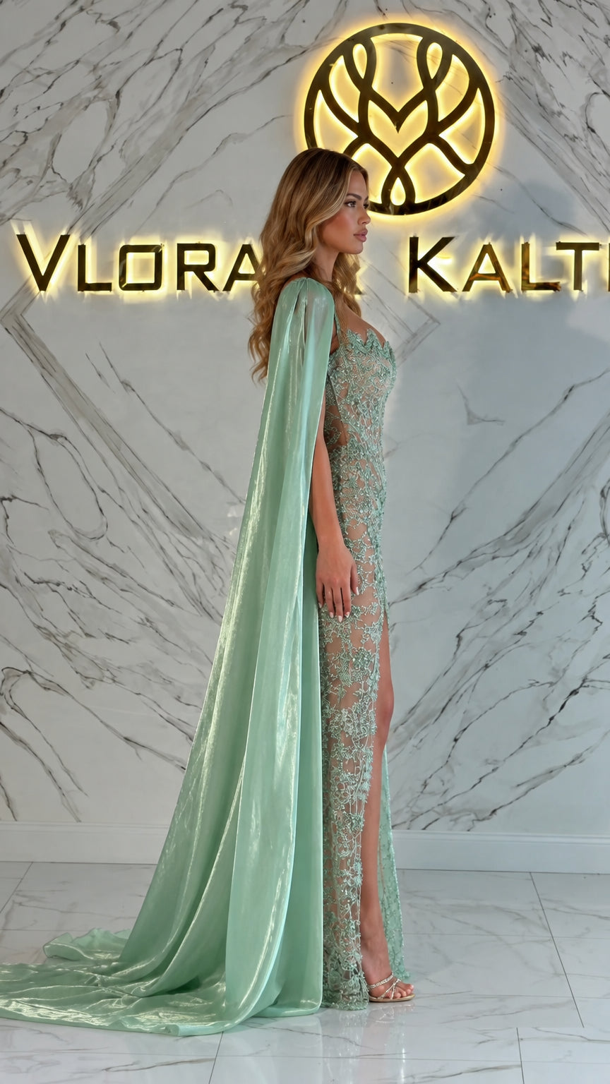 Side angle of mint green embroidered formal dress with dramatic flowing cape