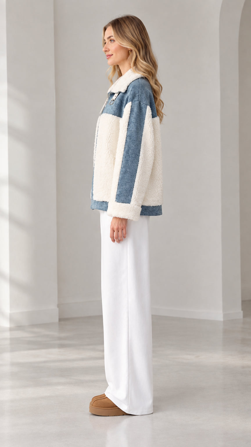 Side profile view of woman wearing blue denim and cream sherpa fleece jacket with white trousers