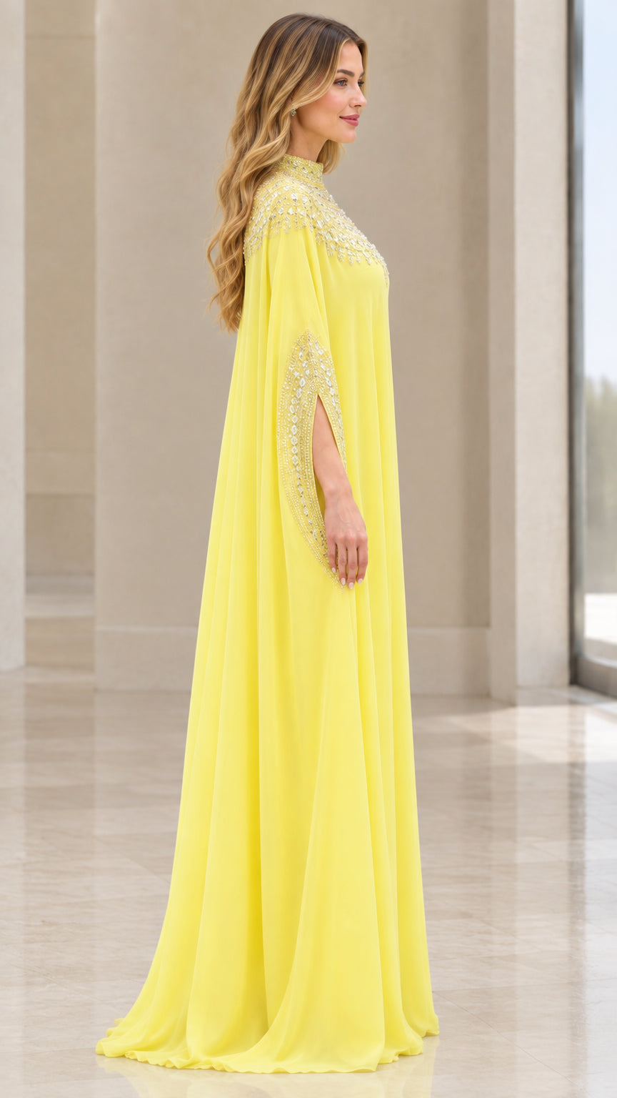 Side angle of model in flowing yellow beaded kaftan gown