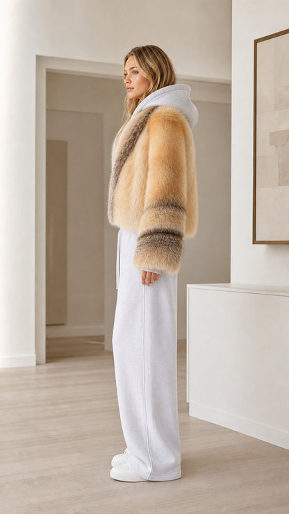Side view of camel faux fur cropped hooded jacket styled with white trousers