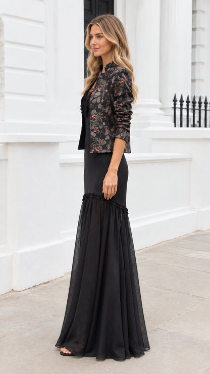 Side three-quarter view of elegant black two-piece formal gown with matching floral jacket