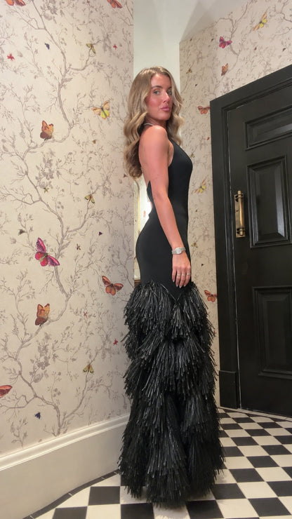 Side profile view of woman wearing black halter fringe mermaid gown