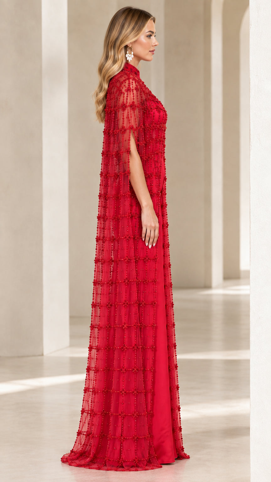 Side profile of woman wearing red cape evening gown with arm opening