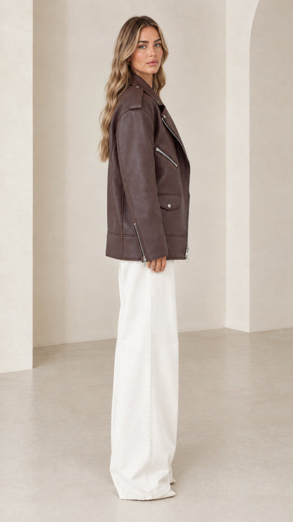 Side profile view of woman modeling dark brown oversized faux leather biker jacket