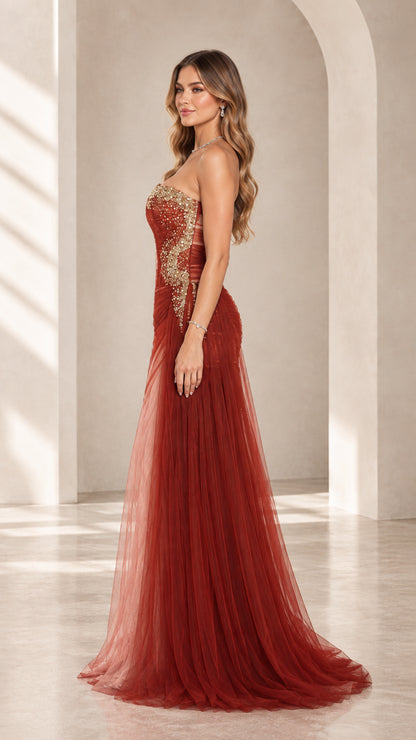 Side angle view of rust red pleated corset gown with flowing sheer tulle skirt