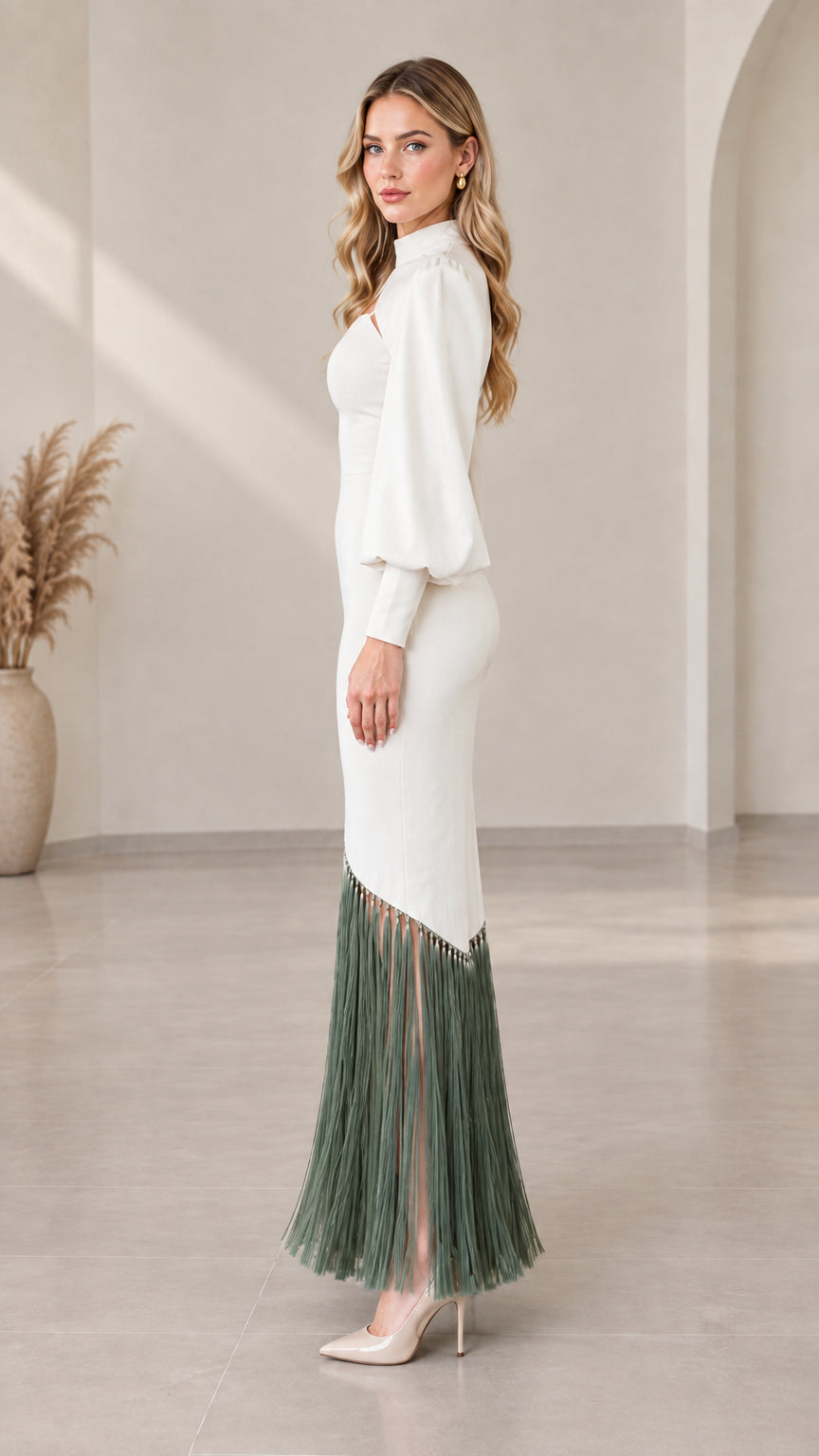 Side view of model wearing white long sleeve cutout evening dress with fringe trim