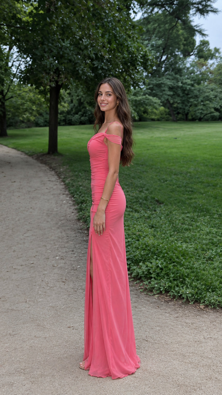 Model wearing the Coral Pink one-shoulder ruched evening gown with front slit in a garden setting