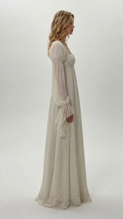 Side profile of model wearing ivory long bell sleeve empire waist dress