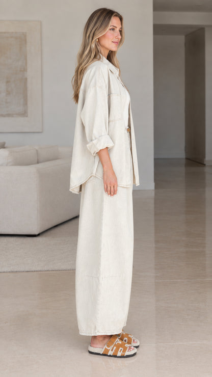 Side angle view of women wearing cream oversized shirt and wide-leg trousers set