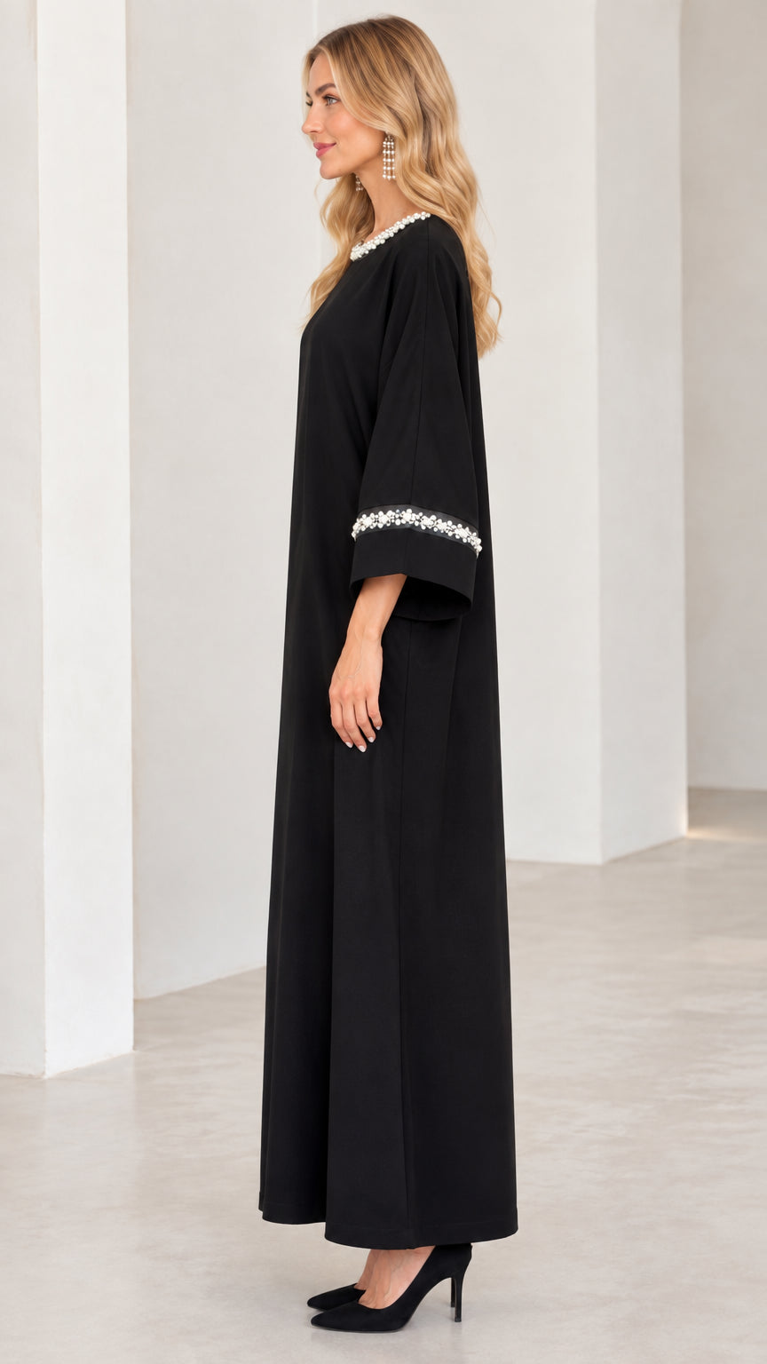 Side profile of woman in black long sleeve pearl trim abaya dress
