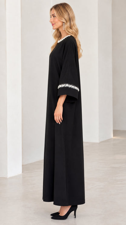 Side profile of woman in black long sleeve pearl trim abaya dress